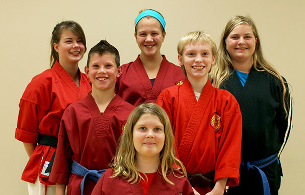 Six people aging from 14 to 20 stand in a triangle formation, smiling and laughing